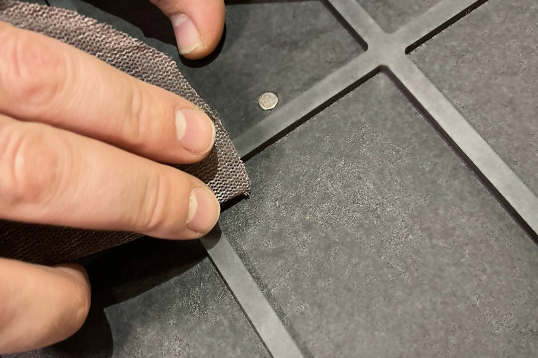 Hand schleift einen schwarzen Rahmen mit Schleifvlies